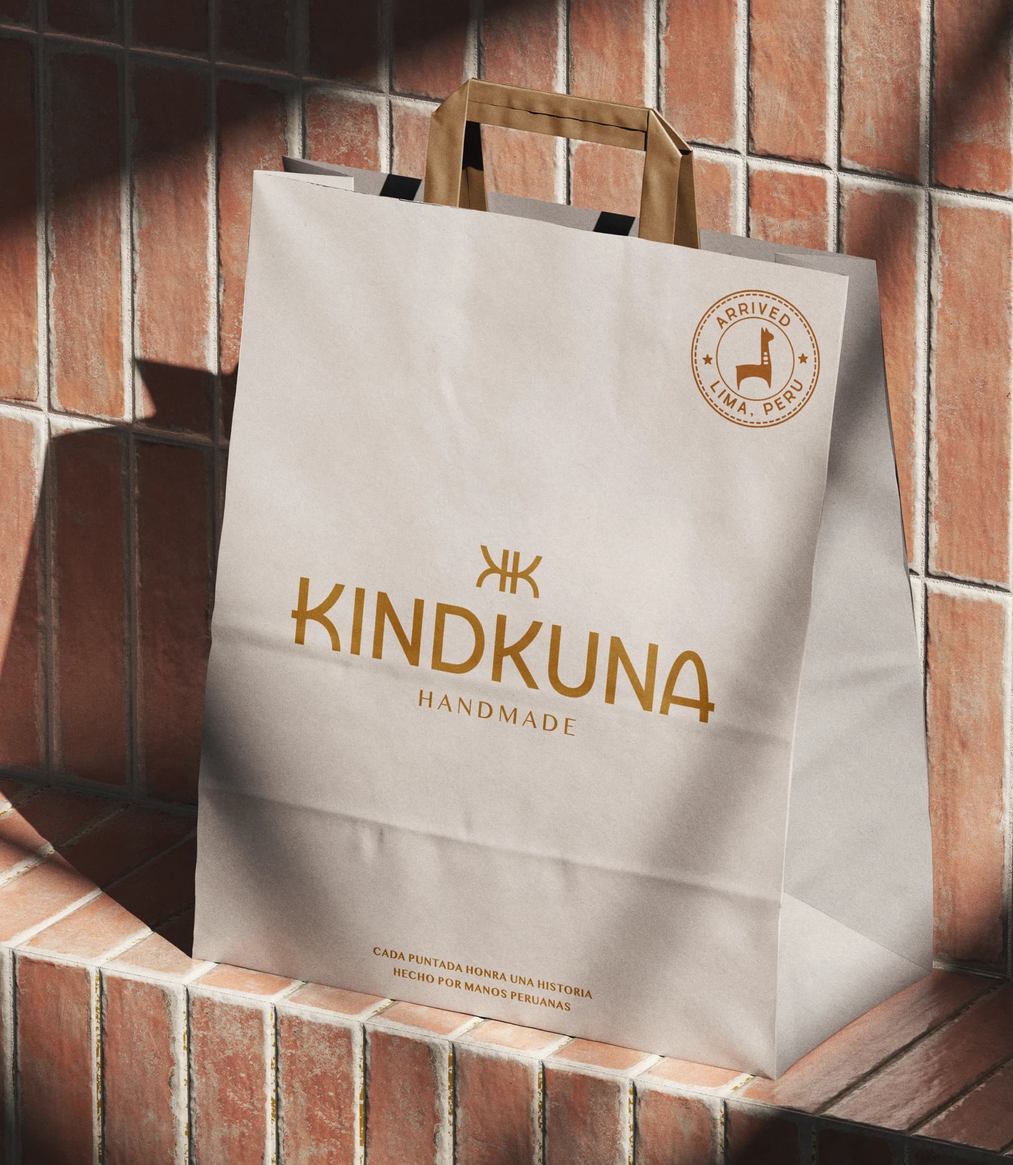 Kindkuna-påse i papper med orange logotyp mot tegelvägg